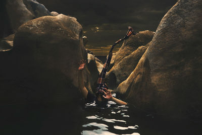 Person face covered with scarf drowning in river amidst rocks