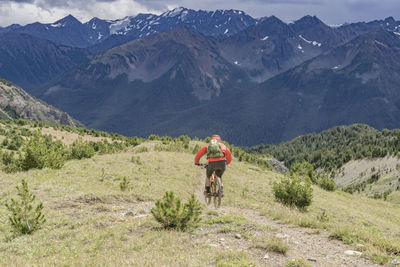 Rear view of man with bicycle on mountain