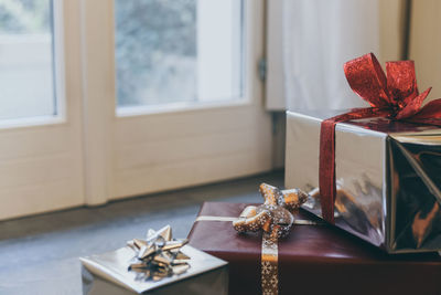 Gift boxes on floor near the door and christmas tree inside home. box with holiday ribbon with bows