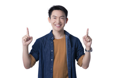 Portrait of smiling young man standing against white background