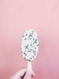 Close-up of hand holding ice cream against gray background