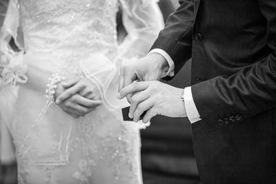 Midsection of couple exchanging ring