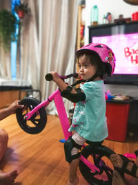 Cute girl riding bicycle on floor at home