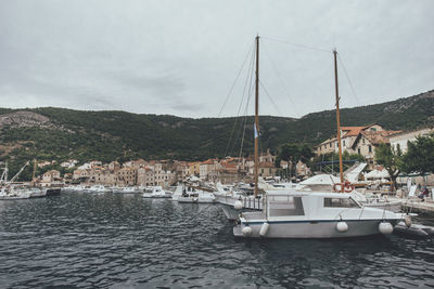 Sailboats moored in sea against sky