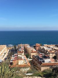 High angle view of cityscape by sea against clear sky