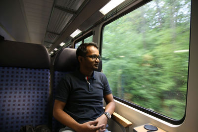 Full length of young man sitting in train in german train during day