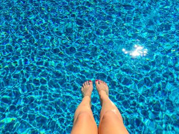 Low section of woman legs in swimming pool