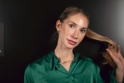 Portrait of young woman against black background