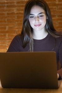 Portrait of young woman using laptop at table