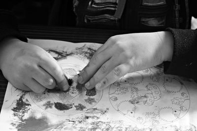 Cropped hands of child painting in paper