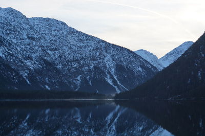 Scenic view of lake by snowcapped mountain against sky