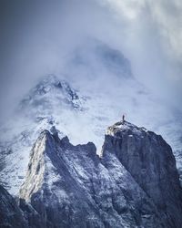 Scenic view of snowcapped mountain with climber in the foreground.