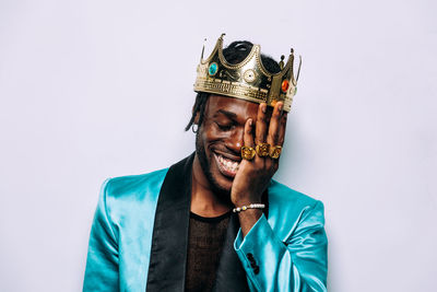 Smiling man wearing crown against white background