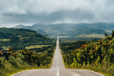 High angle view of empty road leading towards mountains against sky