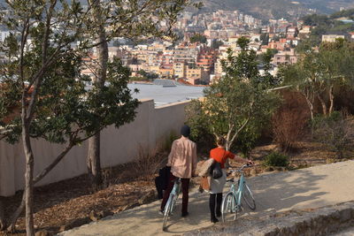 Rear view of man and woman with bicycles on road