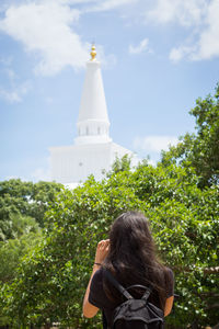 Rear view of woman with umbrella against sky