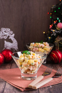 Russian olivier salad of sausage and boiled vegetables in bowls on a wooden table. vertical view
