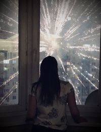 Rear view of woman looking through window