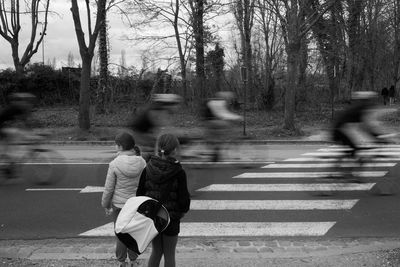 Rear view of people walking on road in city