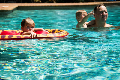 Father with children in swimming pool on sunny day