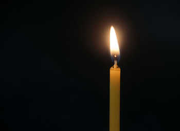 Close-up of illuminated candle in darkroom