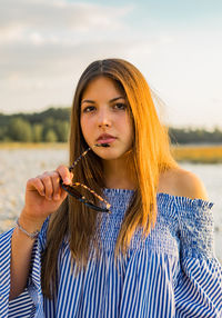 Portrait of beautiful young woman against sky