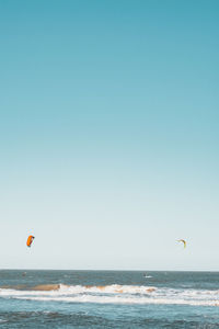 Scenic view of kitesurfers on sea against clear sky