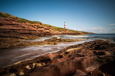 Lighthouse by sea against sky