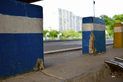 Close-up of wall by road against blue sky
