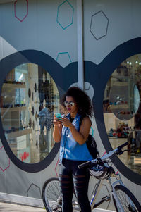 Young woman photographing through smart phone while standing in city