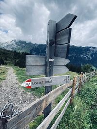 Information sign on road by mountains against sky