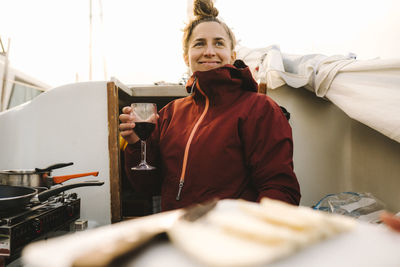 Smiling woman holding glass of wine on boat