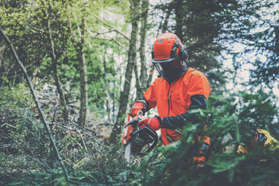 Man holding a chainsaw and cut trees. lumberjack at work . gardener working outdoor in the forest