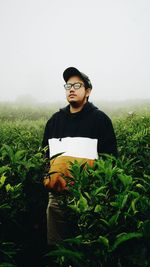 Young man wearing sunglasses standing on field