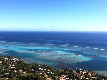 High angle view of townscape by sea against blue sky