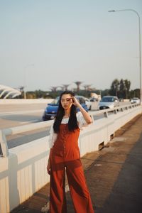 Woman with eyes closed standing on road against sky