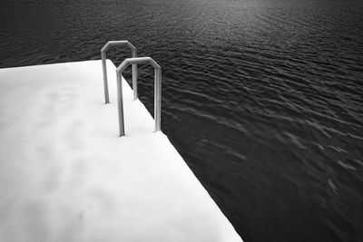 High angle view of metallic railing on snow covered lakeshore