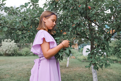 Portrait of young woman standing against trees