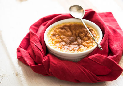 High angle view of fresh souffle served in bowl with spoon and red napkin on table