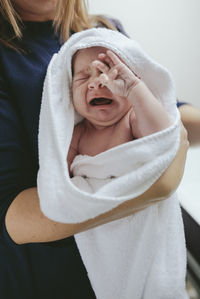 Midsection of mother holding son in towel at bathroom