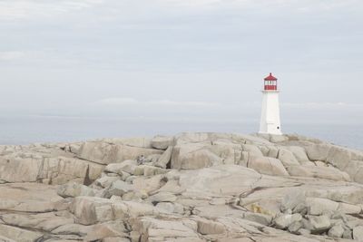Lighthouse on rocky field against sky at peggys cove
