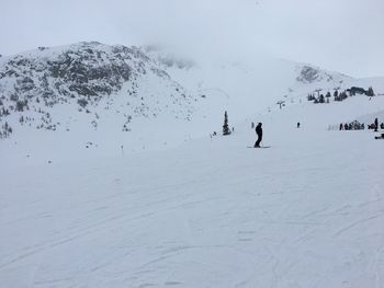 People skiing on snow covered mountain against sky