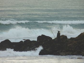 Man fishing at rocky shore