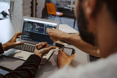 Male hackers doing coding over laptop at startup company