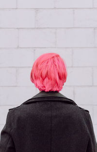 Back view crop unrecognizable female with dyed hair standing near white wall