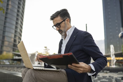 Businessman with clipboard working on laptop