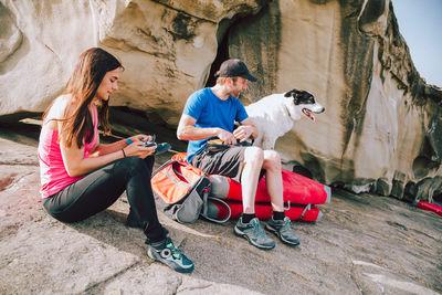 Full length of people with dog sitting on rock