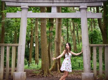 Portrait of woman standing against torii gate