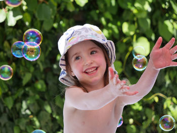 Smiling shirtless girl playing with bubbles