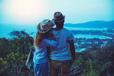 Rear view of couple looking at sea while standing on mountain